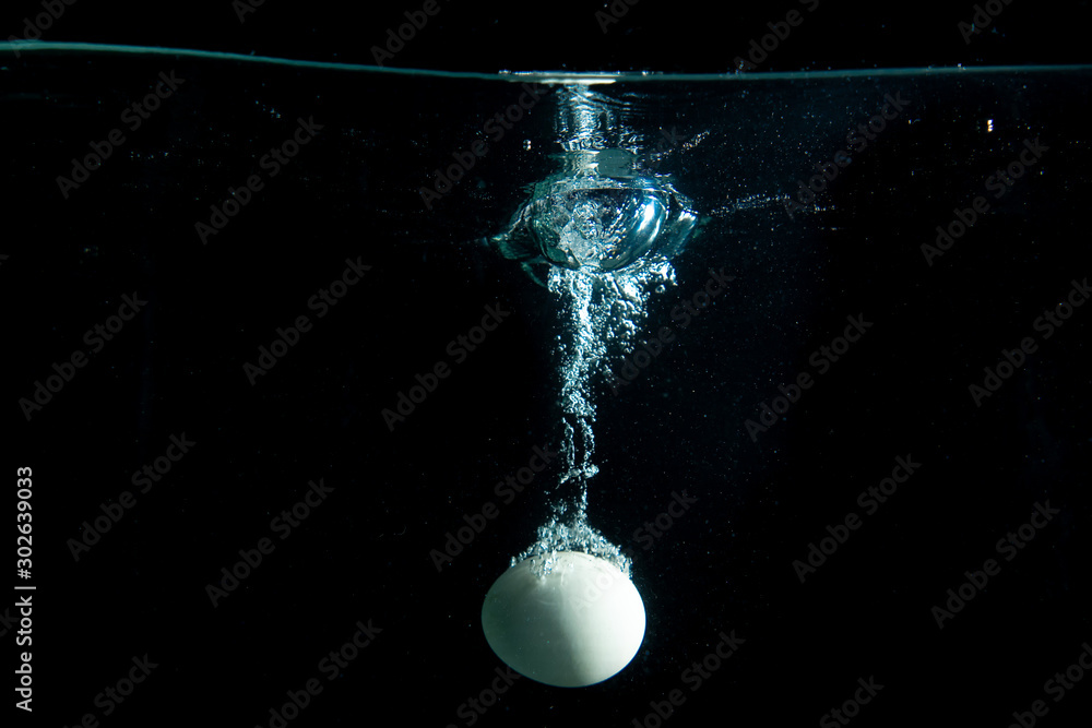 drop egg in tank. water is splash on black background drop egg in tank. water is splash on black background