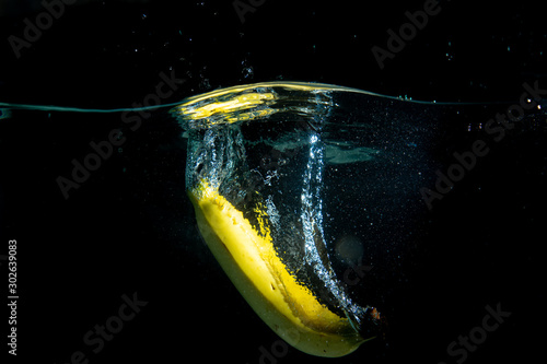 drop banana in tank. water is splash on black background