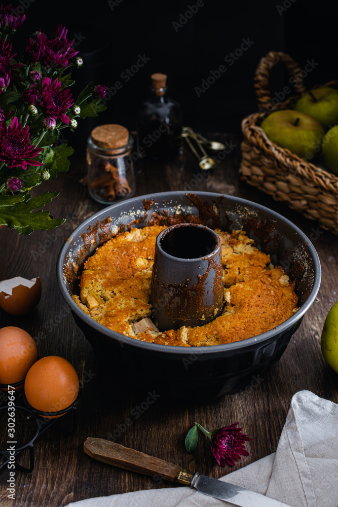 apple bundt cake on dark wooden table, eggs, cinnamon, vanilla extract apple bundt cake on dark wooden table, eggs, cinnamon, vanilla extract