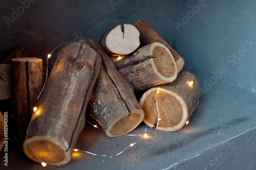 Logs of a tree are located on the wall. Imitation of a fireplace in the wall, lights of a garland with logs