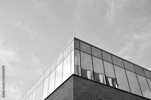 Curtain wall made of toned glass and steel constructions under sky. A fragment of a building. Black and white.