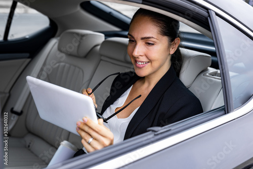 Beautiful Young Businesswoma is working on her tablet in the Car