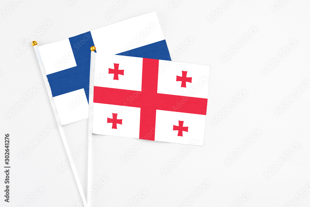 Georgia and Finland stick flags on white background. High quality fabric, miniature national flag. Peaceful global concept.White floor for copy space.