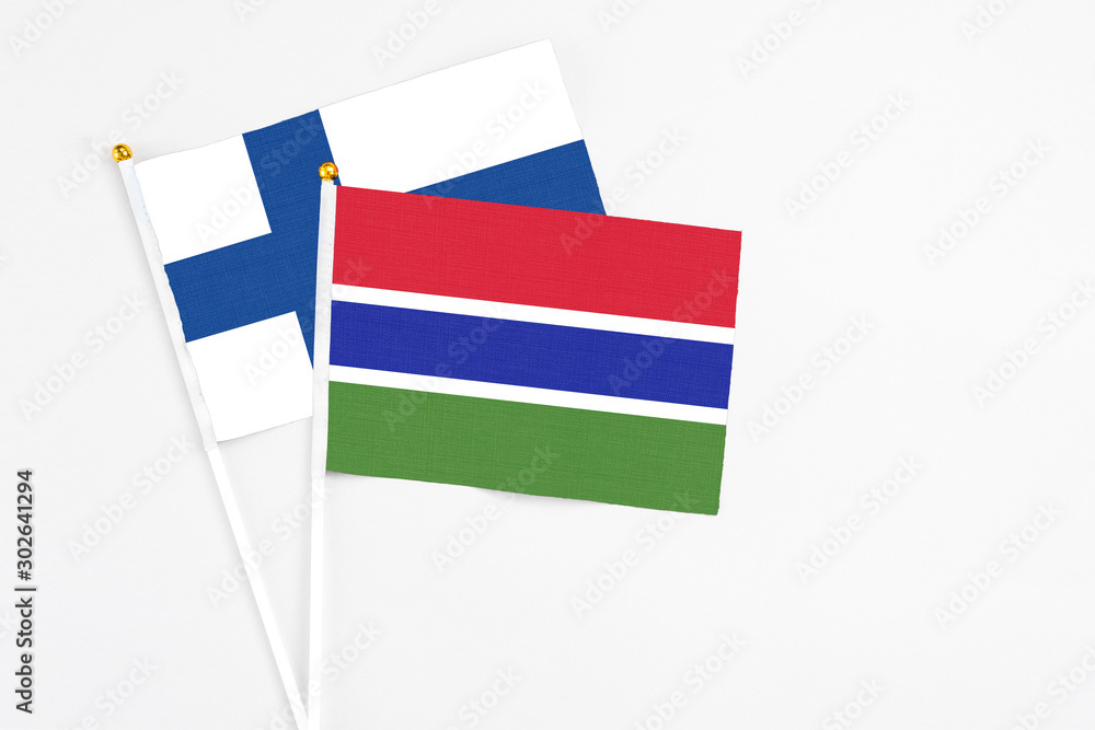 Gambia and Finland stick flags on white background. High quality fabric, miniature national flag. Peaceful global concept.White floor for copy space.