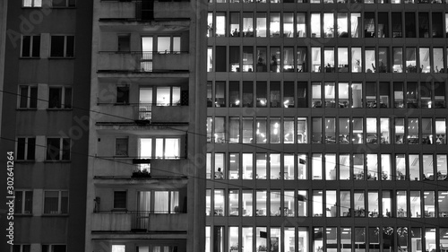 Pattern of office buildings windows illuminated at night. Lighting with Glass architecture facade design with reflection in urban city. Black and white.