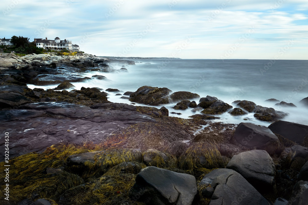The coast of the Atlantic Ocean. Waves breaking on stones, the running of clouds and water underlined by a long exposure. Minimalistic seascape. USA. Maine The coast of the Atlantic Ocean. Waves breaking on stones, the running of clouds and water underlined by a long exposure. Minimalistic seascape. USA. Maine