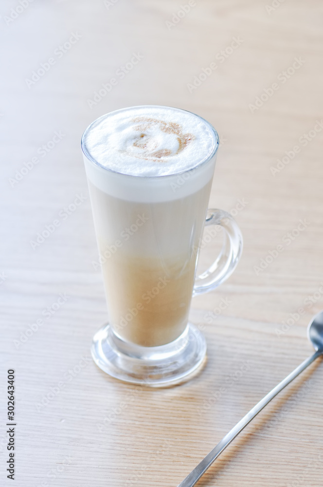 One tall glass of latte on a table. One tall glass of latte on a table.