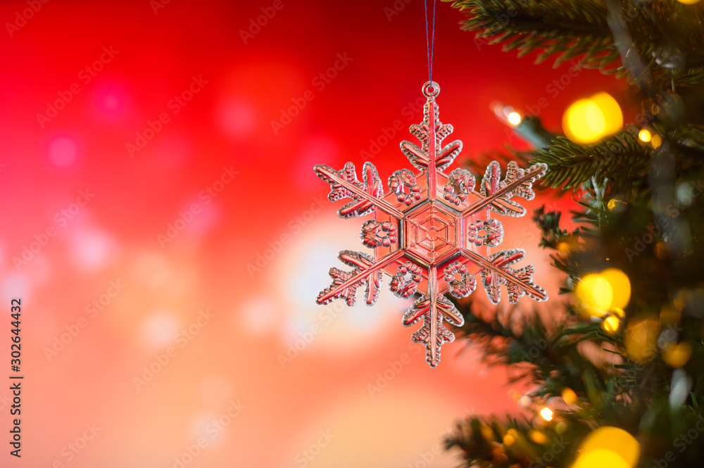 Obraz premium Christmas and background.Toy in the form of a transparent star on a Christmas tree, background for a card, dark red bokeh background, Greeting card for a congratulation for design. Inscription