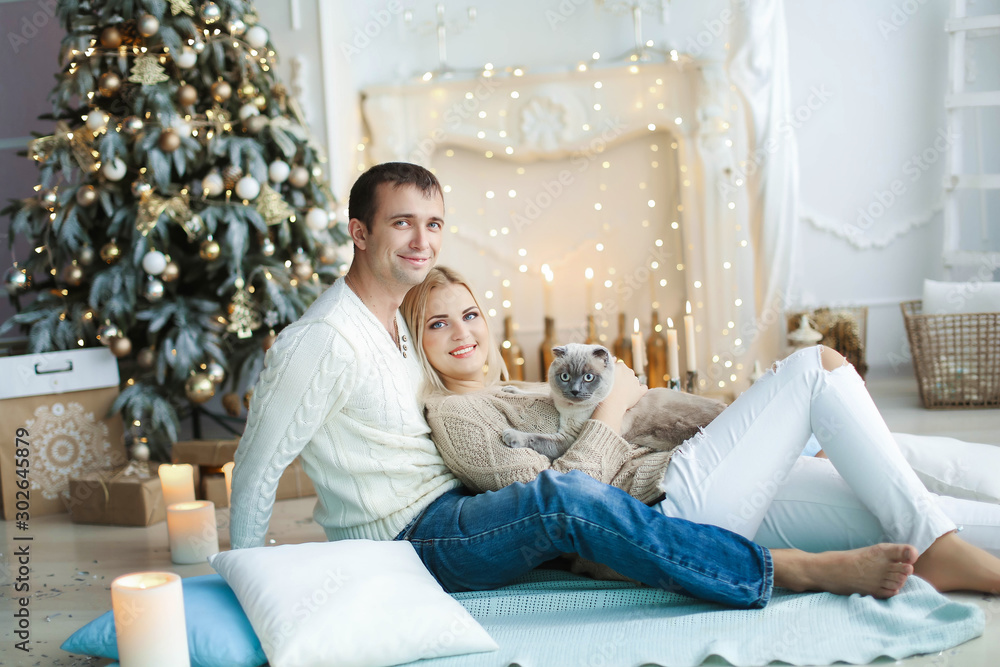 A pair of lovers in anticipation of the celebration of the new year on the background of decorated home interior. A pair of lovers in anticipation of the celebration of the new year on the background of decorated home interior.