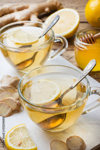 Two cups of natural herbal tea ginger lemon and honey on a wooden background.