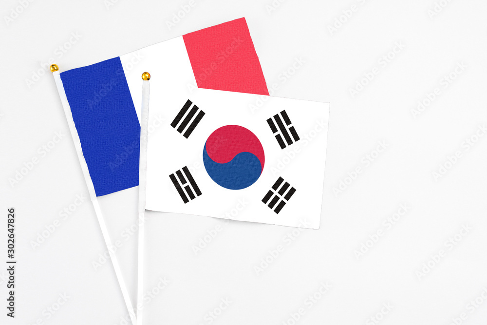 South Korea and France stick flags on white background. High quality fabric, miniature national flag. Peaceful global concept.White floor for copy space.