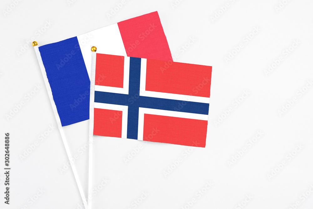 Norway and France stick flags on white background. High quality fabric, miniature national flag. Peaceful global concept.White floor for copy space.