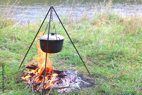 cooking delicious tasty food outdoors on fire in in summer in good weather with wood from forest