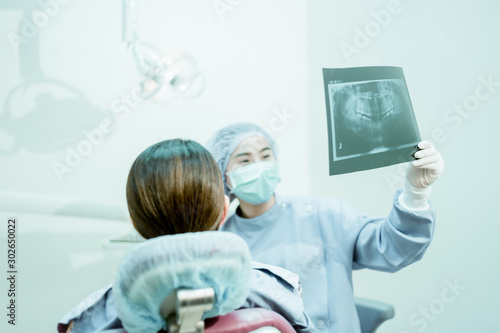 Female dentist shows the x-ray of the patient's teeth in the dental clinic.