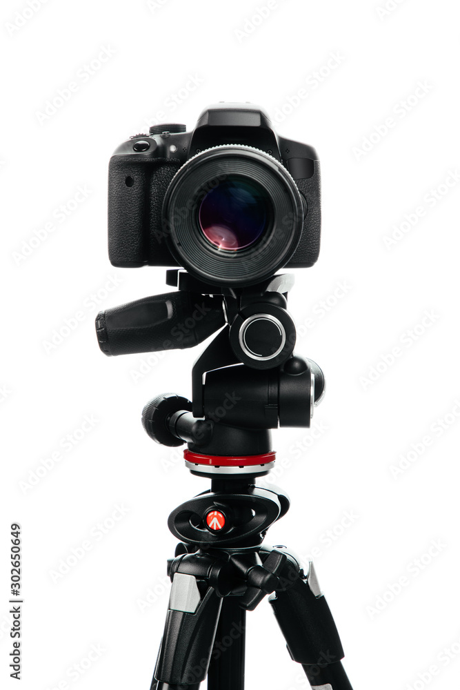 Photo camera with lens on the tripod. Studio shot on white isolate background