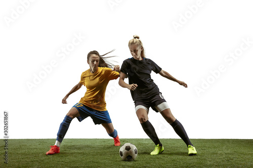 Young female soccer or football players with long hair in sportwear and boots training on white background. Concept of healthy lifestyle, professional sport, motion, movement. Fight for goal.