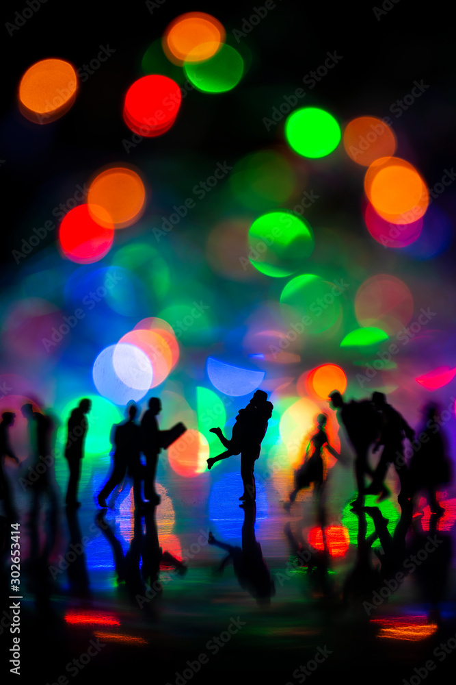 Miniature toy - Silhouette of a couple hugging together among busy commuters crowd with colorful bokeh lights, happiness concept.