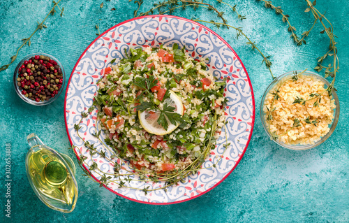 Tabule salad of bulgur, tomatoes, spices, dill on a blue background. Traditional oriental cuisine.