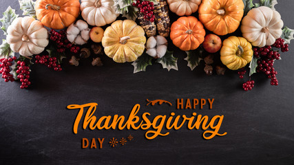 Top view of  Autumn maple leaves with Pumpkin and red berries on black wooden background. Thanksgiving day concept.