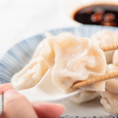 Fresh, delicious boiled pork, shrimp gyoza dumplings on white background with soy sauce and chopsticks, close up, lifestyle. Homemade design concept.