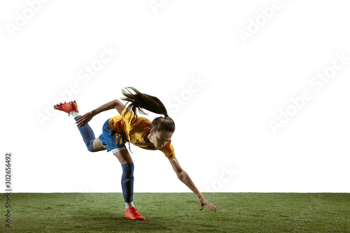 Young female soccer or football player with long hair in sportwear and boots kicking ball for the goal in jump on white background. Concept of healthy lifestyle  professional sport  motion  movement.