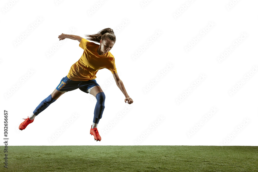 Young female soccer or football player with long hair in sportwear and boots kicking ball for the goal in jump on white background. Concept of healthy lifestyle, professional sport, motion, movement.