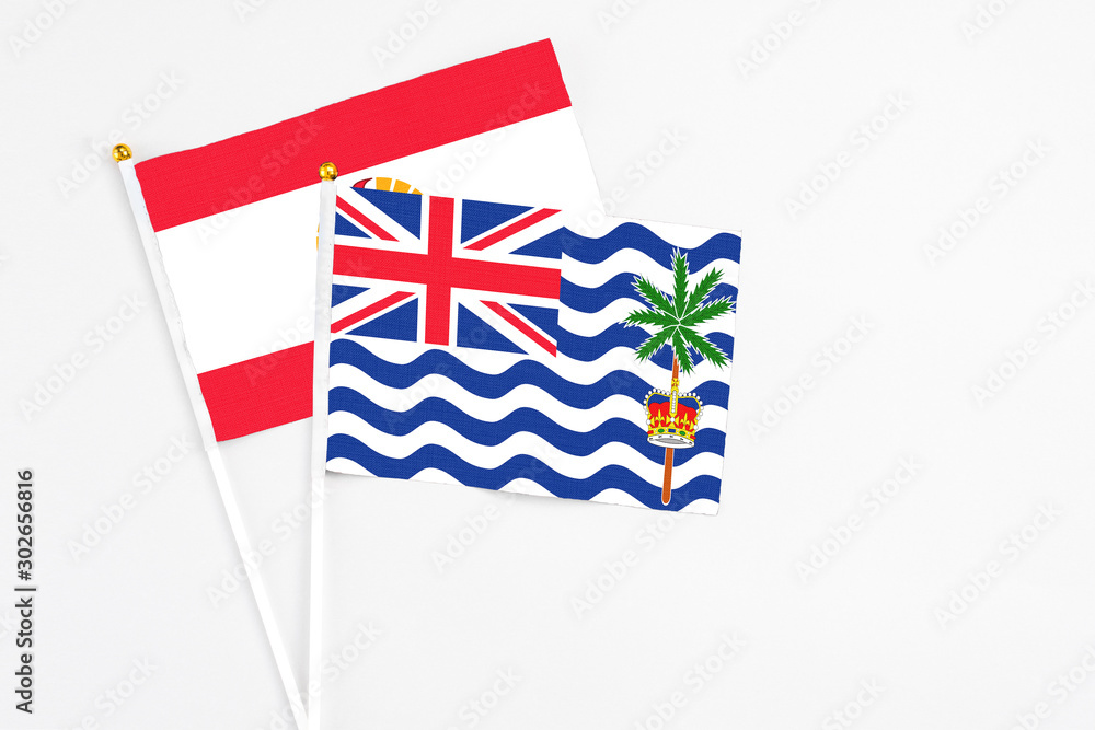 Fototapeta premium British Indian Ocean Territory and French Polynesia stick flags on white background. High quality fabric, miniature national flag. Peaceful global concept.White floor for copy space.