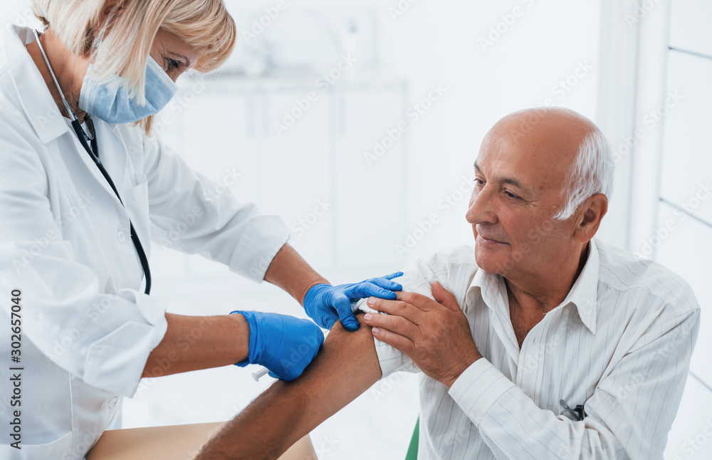 Female doctor injecting senior male patient with syringe in the clinic Female doctor injecting senior male patient with syringe in the clinic