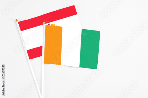 Cote D'Ivoire and French Polynesia stick flags on white background. High quality fabric, miniature national flag. Peaceful global concept.White floor for copy space.