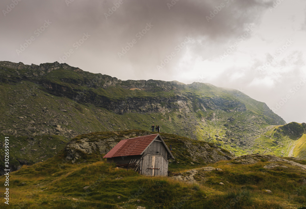 Scenic view of old,small cottage and tourists in Fagaras mountains, Romania