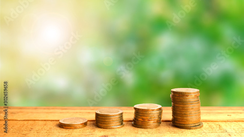 Golden coin stack on wooden table, blur background and sunlight