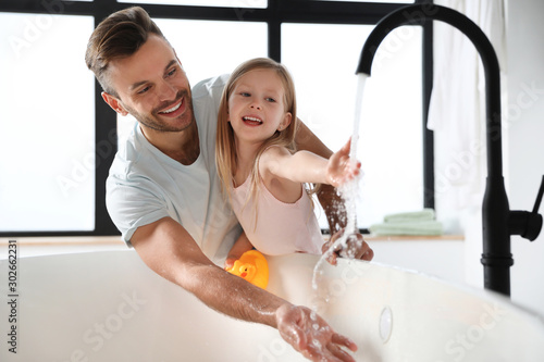 Fotografia Father with his cute little daughter filling tub in bathroom