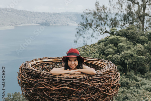 Pretty Asian woman is sitting on straw nest, Wanagiri hidden hill, Bali. photo