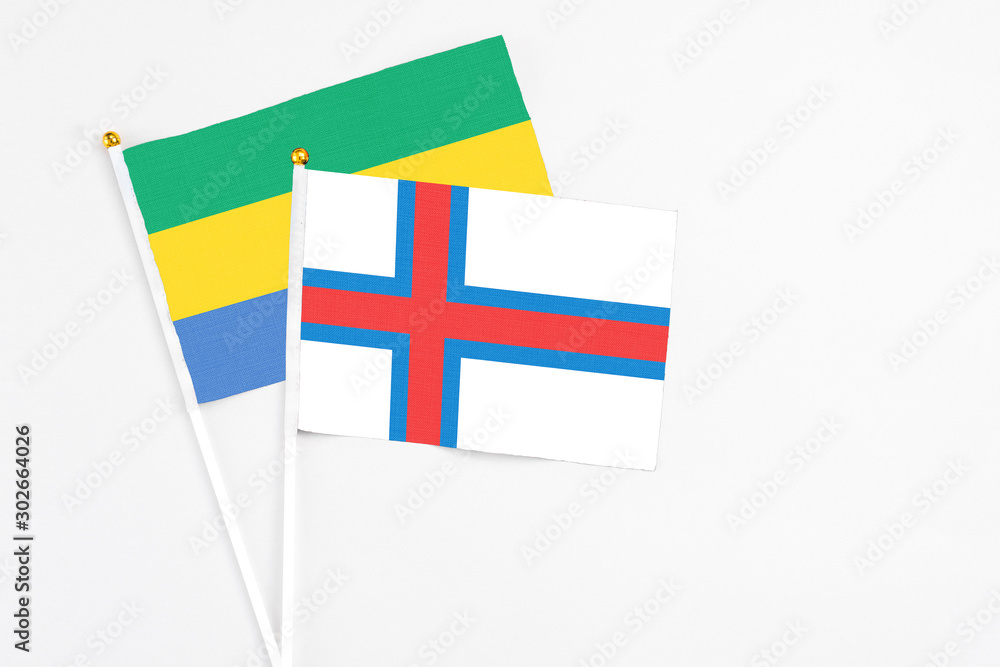 Faroe Islands and Gabon stick flags on white background. High quality fabric, miniature national flag. Peaceful global concept.White floor for copy space.