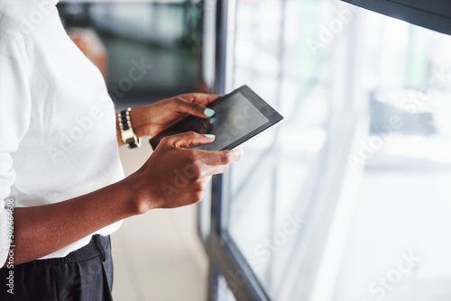 Particle view of african american girl that stands indoors in the office with tablet in hands