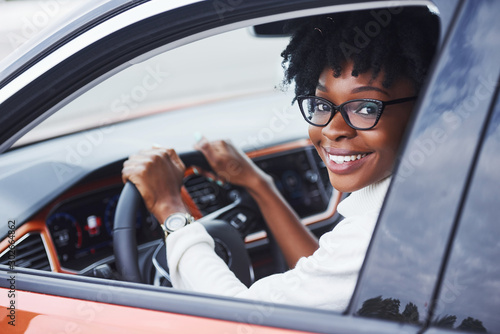 Photography Young african american woman sits inside of new modern car