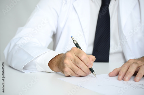 Doctor con bata blanca escribiendo sobre folios