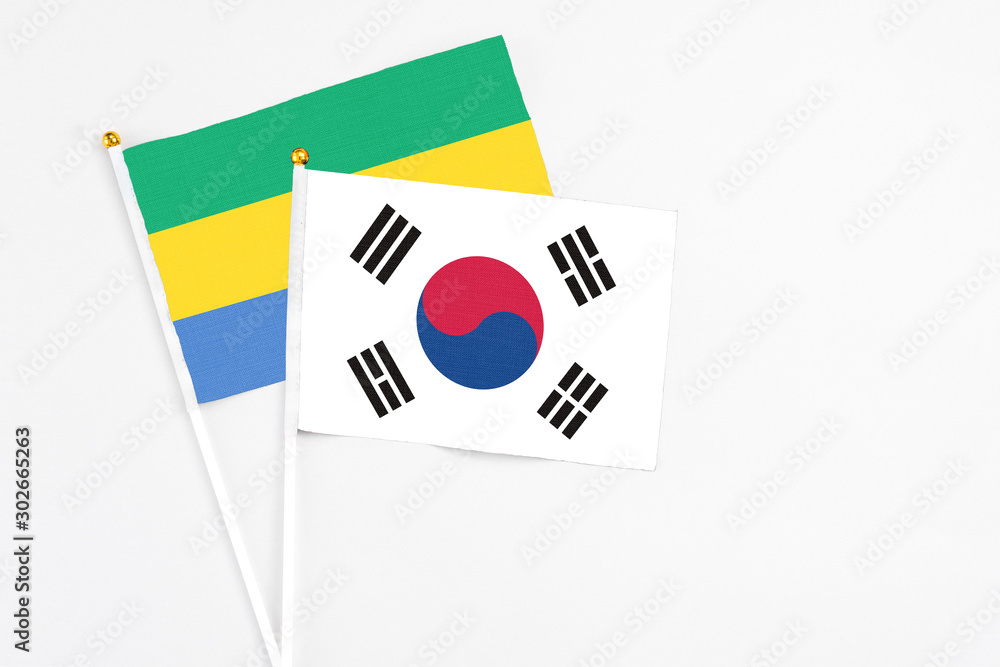 South Korea and Gabon stick flags on white background. High quality fabric, miniature national flag. Peaceful global concept.White floor for copy space.