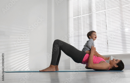 Young woman doing exercise with her son indoors. Home fitness
