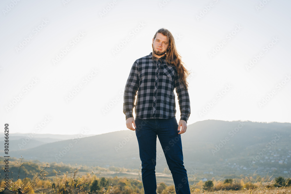 Portrait of handsome thinking young man looking at camera. Young handsome attractive bearded model man in urban context.