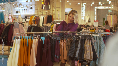 Woman sorts things out on a hanger in a store © iaginzburg