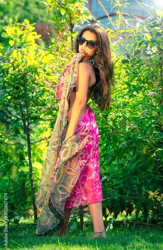 Portrait of beautiful young brown teenager model with poreo, in summer colorful swimsuit posing on the sea coast. young beautiful young girl in a bathing suit on the beach. Fashion and glamor concept.
