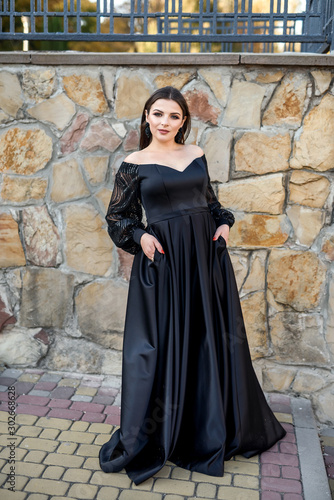 Fashion smiling woman in black dress on a brick background. Fashion © RomanR