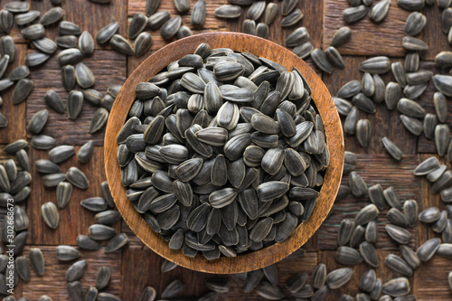 shelled sunflower seeds in wooden bowl, top view.