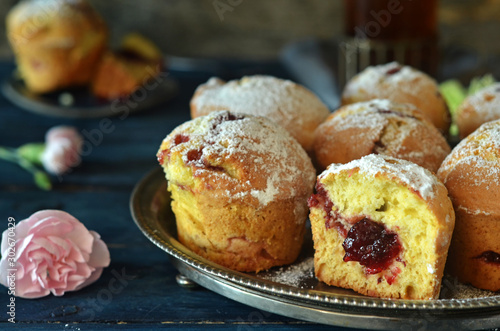 Muffins with jam on a metal, round tray on a wooden background