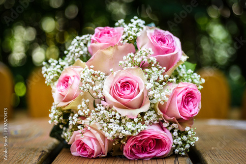 Wedding bouquet with pink roses on wooden table.