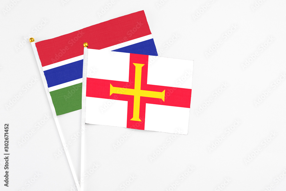 Guernsey and Georgia stick flags on white background. High quality fabric, miniature national flag. Peaceful global concept.White floor for copy space.