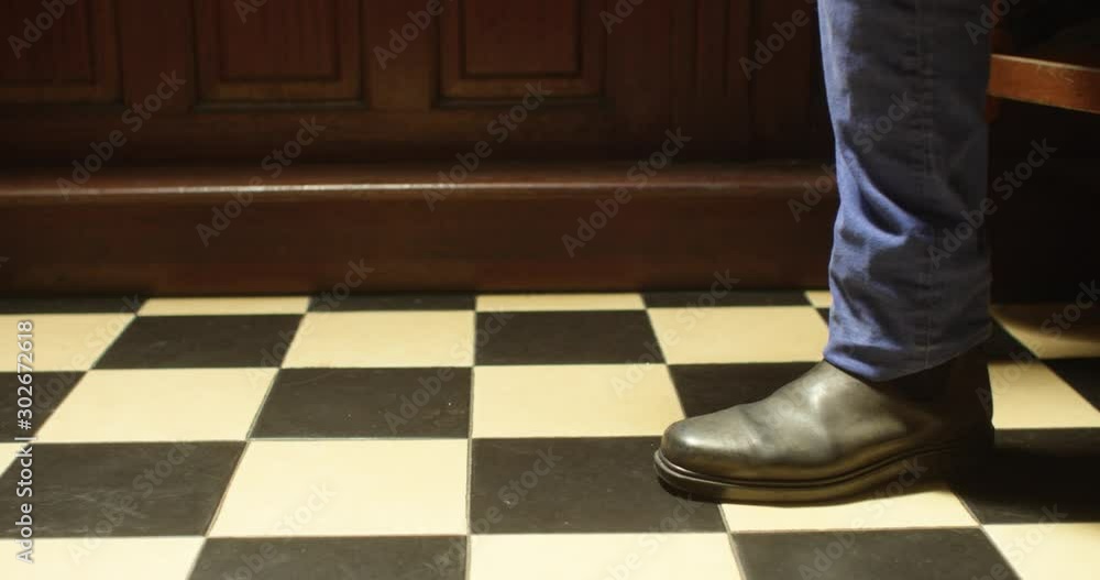 A man drops his phone on the floor at a bar and stomps on it before drunkenly stumbling away. Low angle close-up shot of his feet and the checker tiled bar floor. A man drops his phone on the floor at a bar and stomps on it before drunkenly stumbling away. Low angle close-up shot of his feet and the checker tiled bar floor.
