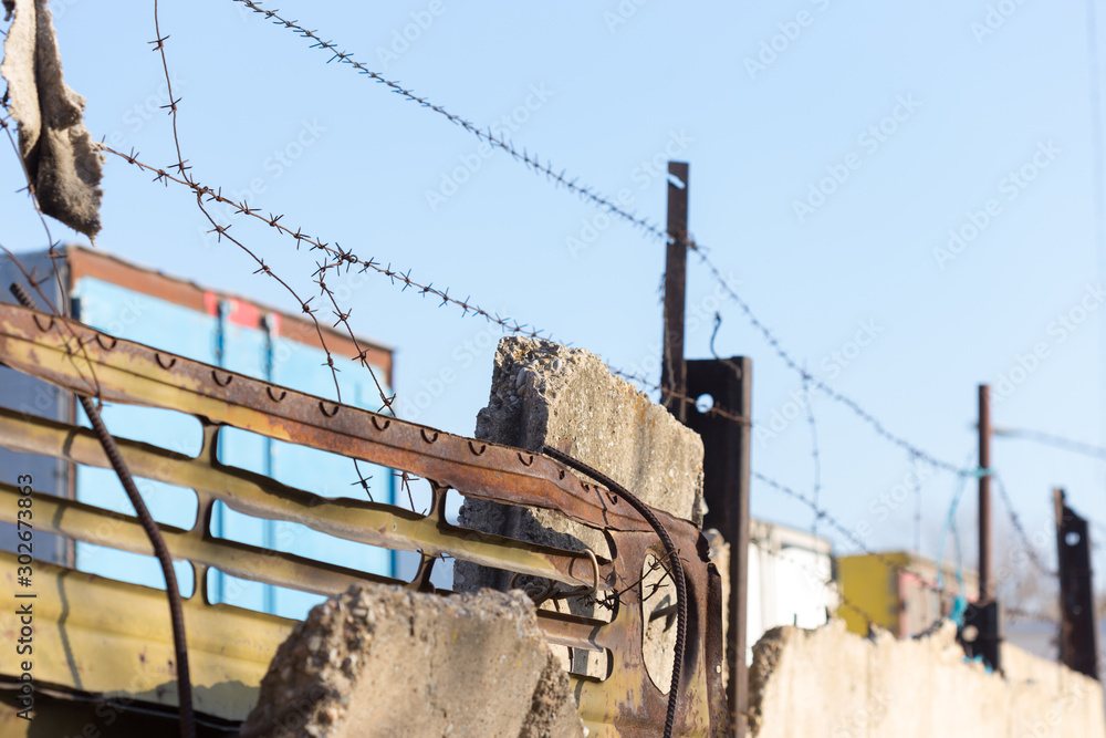 barbed wire with spikes over a concrete fence in the background of blue sky