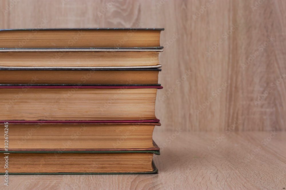 A stack of old books of different colors on a beige background. Yellow faded pages of the book, crumpled corners, of different size. A stack of old books of different colors on a beige background. Yellow faded pages of the book, crumpled corners, of different size.